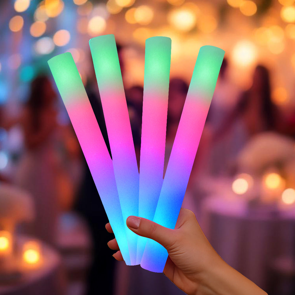 Four multicolor LED foam sticks with green, pink, and blue glow at a wedding reception with warm bokeh lights