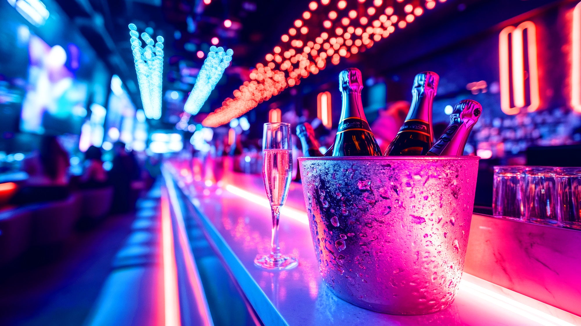 Bottles of champagne in an ice bucket on a bar with colorful lights in the background
