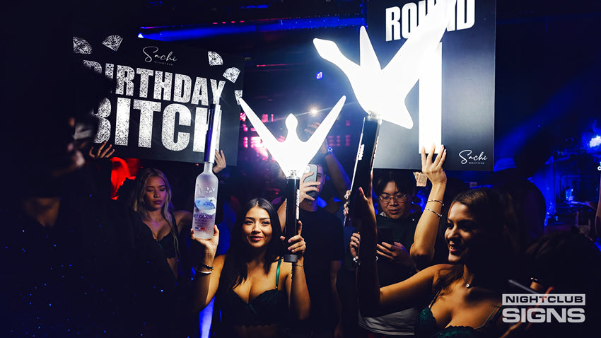 Friends cheering together in a nightclub during a birthday celebration with bottle service